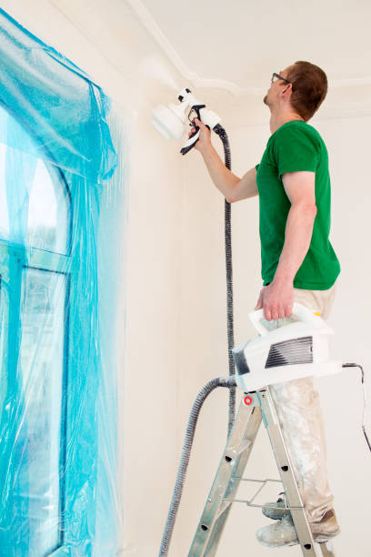 istock Man painting walls with paint spray gun. 996442734