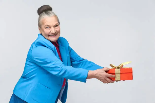 Photo of happy aged woman holding and sharing gift box.