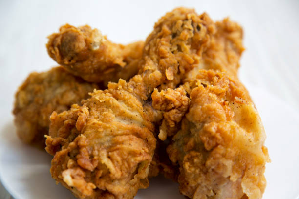 istock Fried chicken drumsticks on a white round plate, close-up. Side view. 996474932