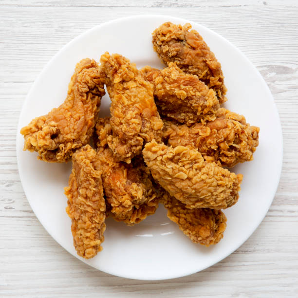 istock Chicken wings on a round white plate over white wooden surface, view from above. Top view, flat lay. 996474994