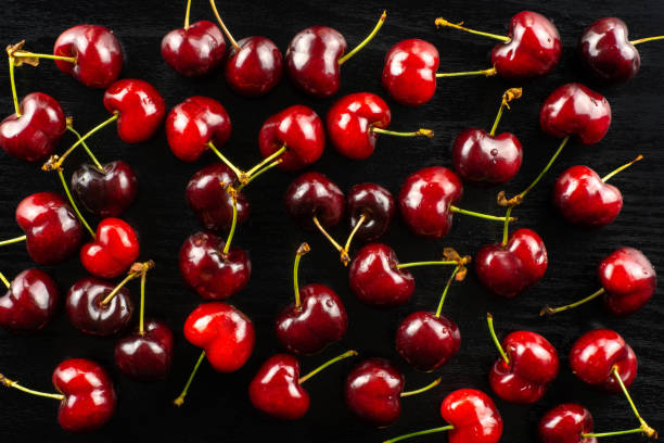 Fresh raw sweet red cherry on black wood