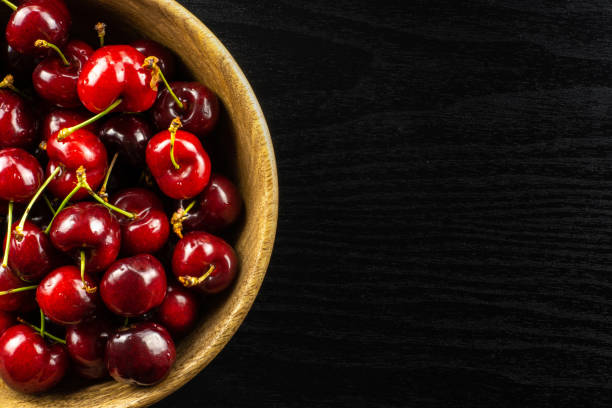 Fresh raw sweet red cherry on black wood