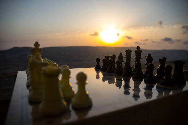 istock chess board game concept of business ideas and competition and strategy ideas. Chess figures on a chessboard outdoor sunset background. 996490202