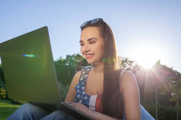 pretty young woman sitting on bean bag use laptop while resting on grass in park on the sun - coffee bean bag human hand imagens e fotografias de stock