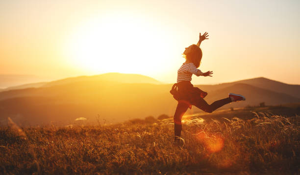 mujer feliz saltando y disfrutando la vida al atardecer en las montañas - autumn glory fotografías e imágenes de stock