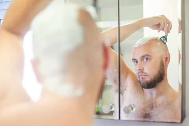 istock Man shaving head in the bathroom mirror 996510468
