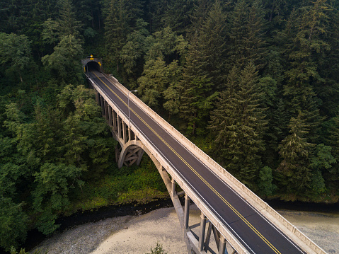 Aerial view of U.S. Route 101 - the Oregon Coast Highway - crossing Cape Creek Bridge near Heceta Head, Oregon and disappearing into the dense forest.