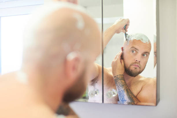 istock Male shaving head in the bathroom mirror 996519744