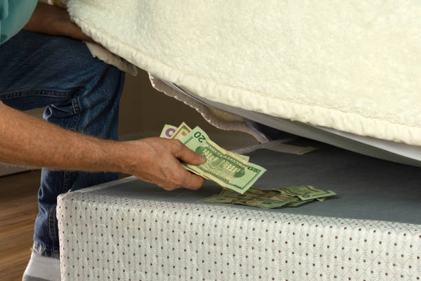 man hiding money under his mattress because he doesn't trust banks - hide imagens e fotografias de stock