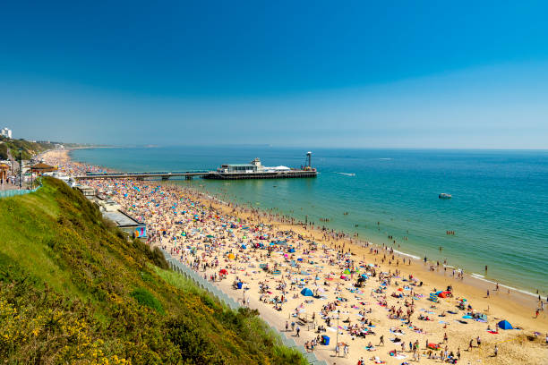Sunbathers pack Bournemouth beach near the Pier Sunshine illuminates golden beaches and blue-green seas along the Dorset coast between Poole and Bournemouth dorset england photos stock pictures, royalty-free photos & images