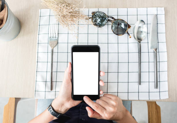istock woman use mobile phone apps at restaurant table.Mobile payment.Digital leisure lifestyle.mock up template for display of content.top view angle.clipping path on screen. 996572954