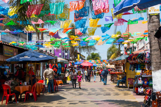 People Shop Below Colorful Hanging Flags in Tijuana, Mexico stock photo