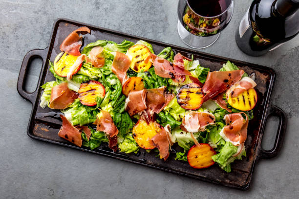 lettuce, ham serrano and grilled peaches salad served on black board with red wine. top view - serrano chilli pepper meat ham spain imagens e fotografias de stock
