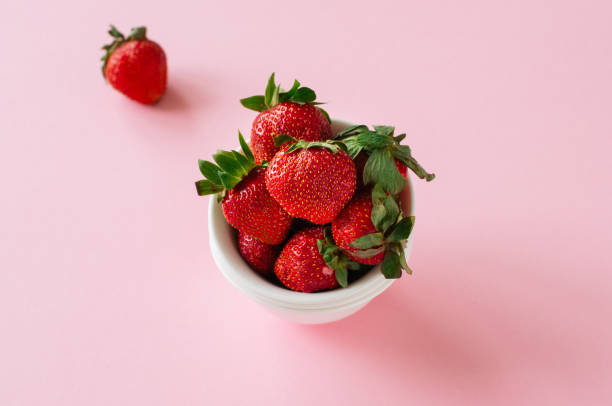 istock Fresh ripe strawberries on a white bowl on a pink background. Co 996615956