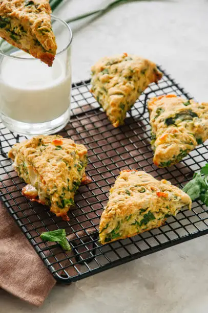 Savory scones with feta mozzarella and green herbs on a wire rack.