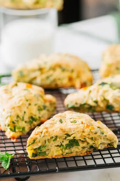 Savory scones with feta mozzarella and green herbs on a wire rack.
