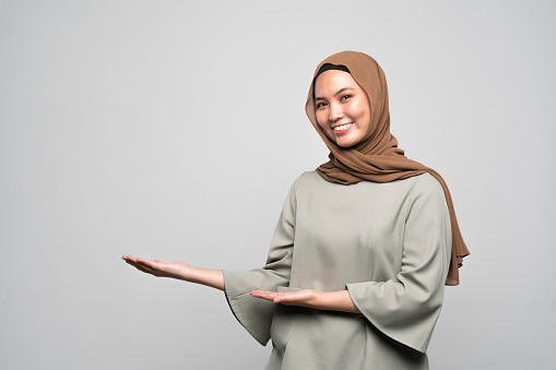 Studio shot of a young Malaysian woman in traditional Muslim clothing, showing the white background.