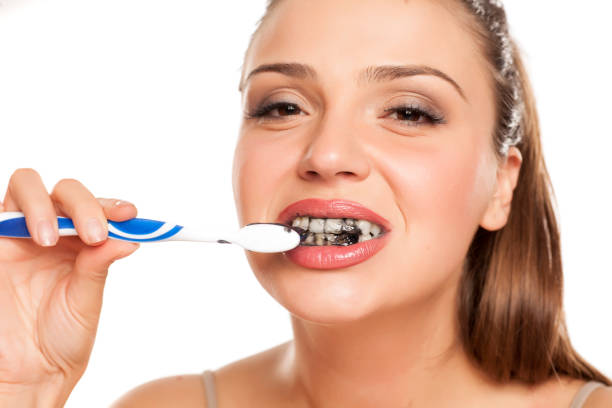 istock young woman brushing her teeth with black toothpaste of activated charcoal on white background 996616542