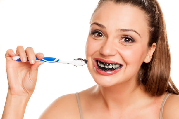 istock young woman brushing her teeth with black toothpaste of activated charcoal on white background 996616546