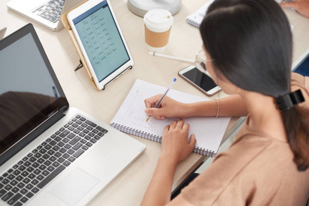 istock Female writing in notebook sitting at workplace 996622374