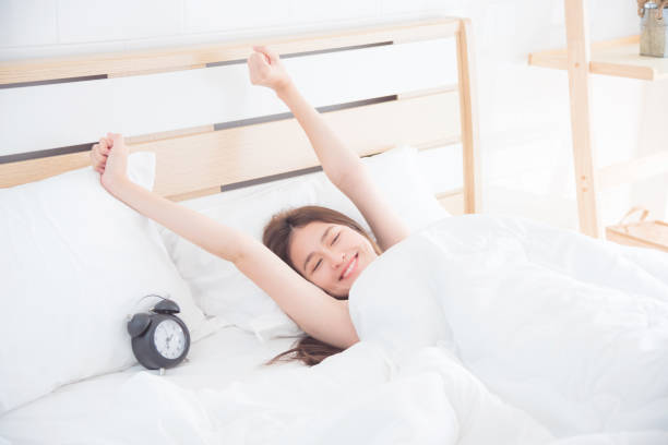 woman stretching on bed in the morning stock photo