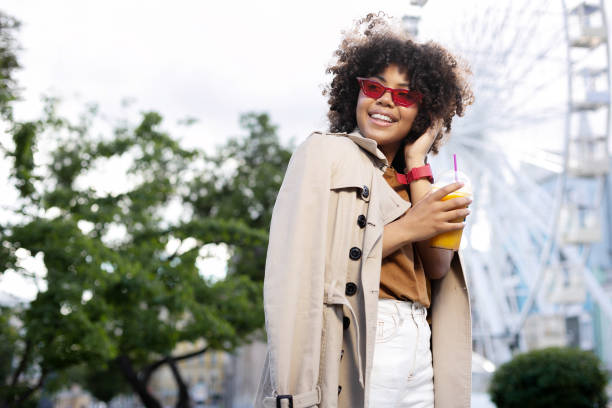 istock Adorable curly woman having juice while walking in park 996627174