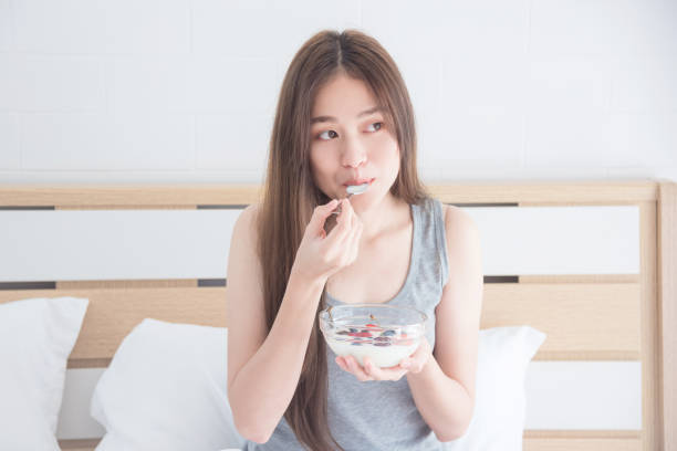 woman eating yogurt with fruits for breakfast stock photo
