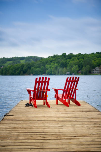 istock Red Muskoka chairs on a wooden dock 996636134