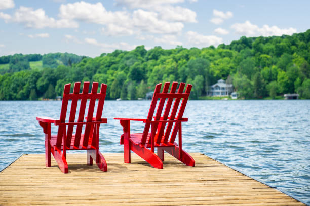 istock Red Muskoka chairs on a wooden dock 996636154