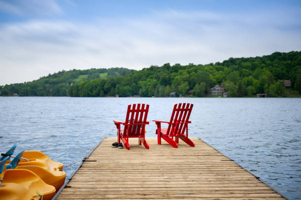 istock Red Muskoka chairs on a wooden dock 996636180