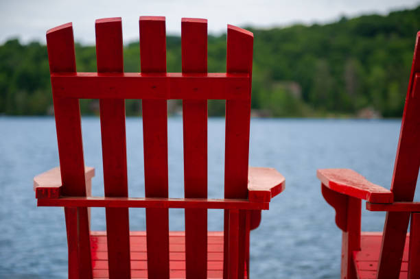 istock Red Muskoka chairs on a wooden dock 996636204