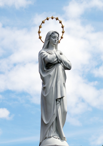 Statue of Virgin Mary as a symbol of love and kindness near catholic church.  White stone statue of Saint Maria.