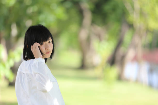 istock Asian young woman thinking and looking portrait with green tree background 996660604