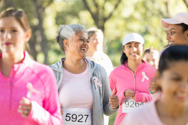 Cheerful senior woman and her daughter during charity walk Beautiful senior woman and her young adult daughter talk as they walk in a breast cancer awareness race. walking for a cause stock pictures, royalty-free photos & images