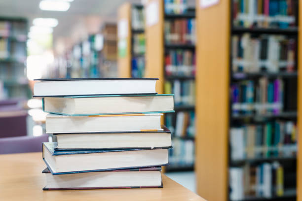 istock Book stack in the library room and blurred bookshelf for business and education background, back to school concept 996671954