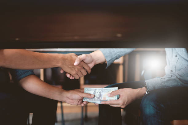 istock Businessmen shaking hands with bribe money under table. Corruption and Anti Bribery concepts. 996672792