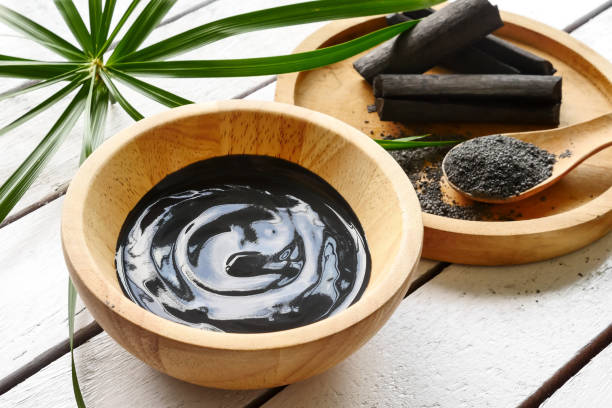 Facial mask and scrub by activated charcoal powder on wooden table Facial mask and scrub by activated charcoal powder on wooden table start button stock pictures, royalty-free photos & images