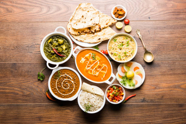 Assorted indian food for lunch or dinner, rice, lentils, paneer, dal makhani, naan, chutney, spices over moody background. selective focus stock photo