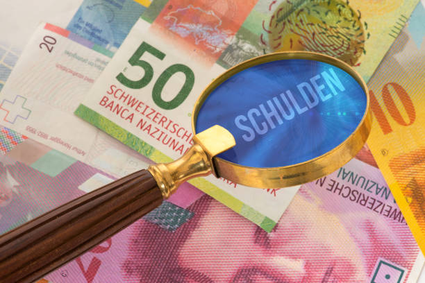 istock Swiss franc banknotes, a magnifying glass and the debt 996701722