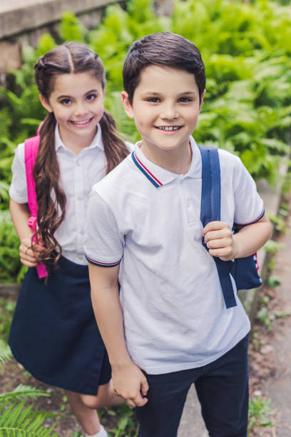 istock happy schoolchildren with backpacks looking at camera in park 996702422