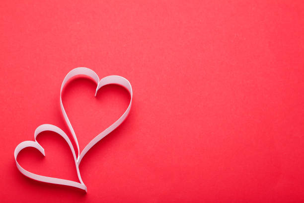 istock White paper hearts on red background 996705536