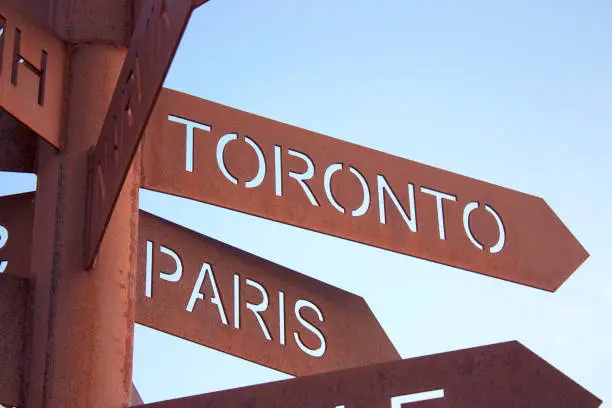 Rusty roadsigns with names of cities Toronto, Paris