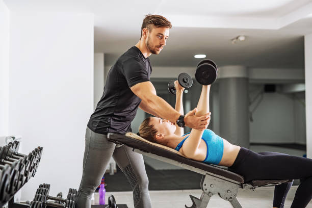 istock Personal trainer with female trainee in gym 996731054