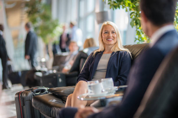 Business people sitting on chair at airport Business people sitting on chair and discussing at airport departure area. black man blonde hair stock pictures, royalty-free photos & images