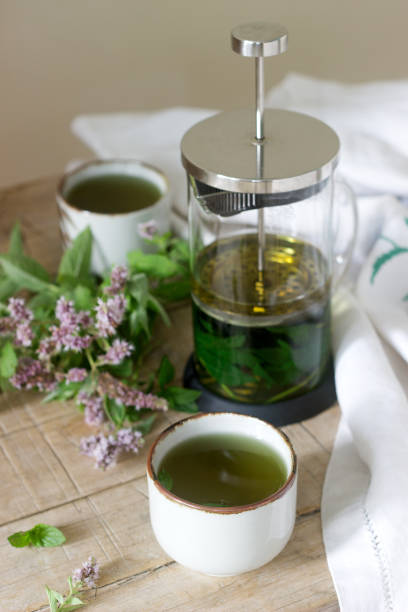 istock Mint tea in a clear glass teapot, mint leaves and tea cups. 996746544