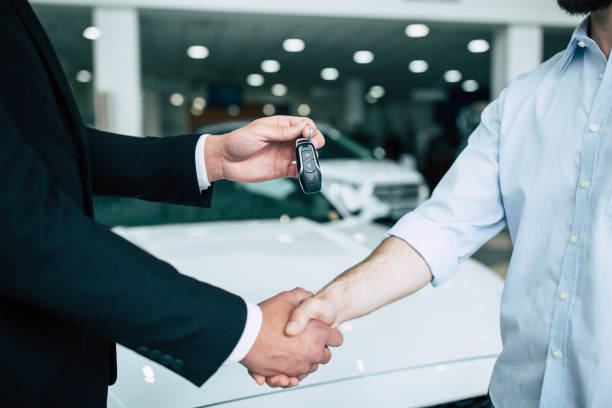 Buying a new car Buying a new car. Handshake and handing over the keys to the car by the salon consultant to the buyer. car ownership photos stock pictures, royalty-free photos & images