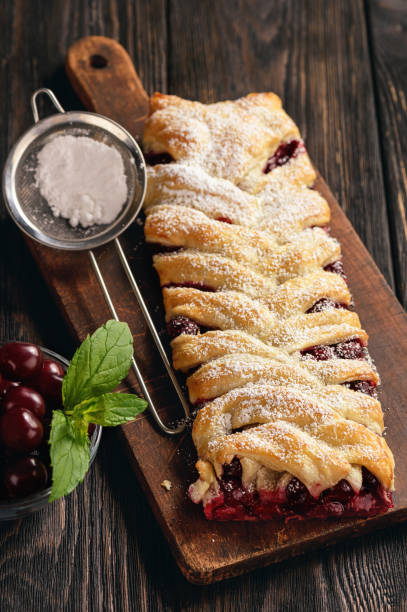 istock Homemade cherry puff pastry braid, on blue wooden background. 996750848