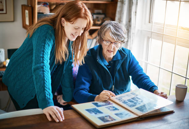 vieja dama muestra a su nieta sonriente el álbum de fotos familiar - compartir fotos fotografías e imágenes de stock