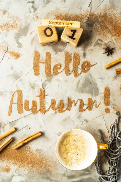 istock Hello, Autumn. The phrase is written with ground cinnamon on a gray background. Next to the wooden calendar on which the date is September 1. Top view, flat lay 996757222