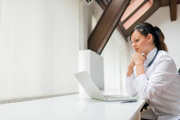 istock Pensive doctor looking at laptop screen in the office. Copy space. 996758086